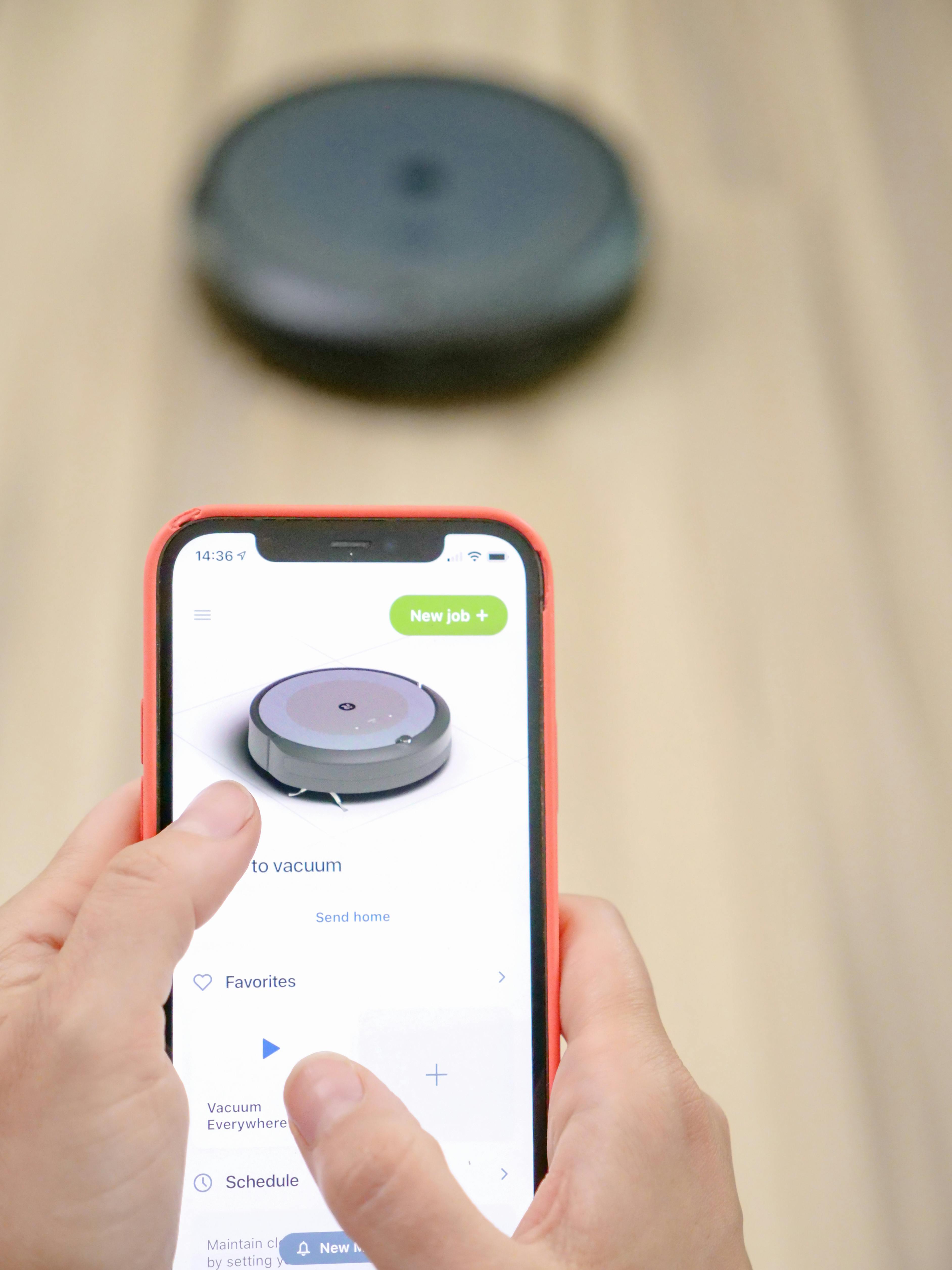 Person controlling smart robot vacuum with mobile app